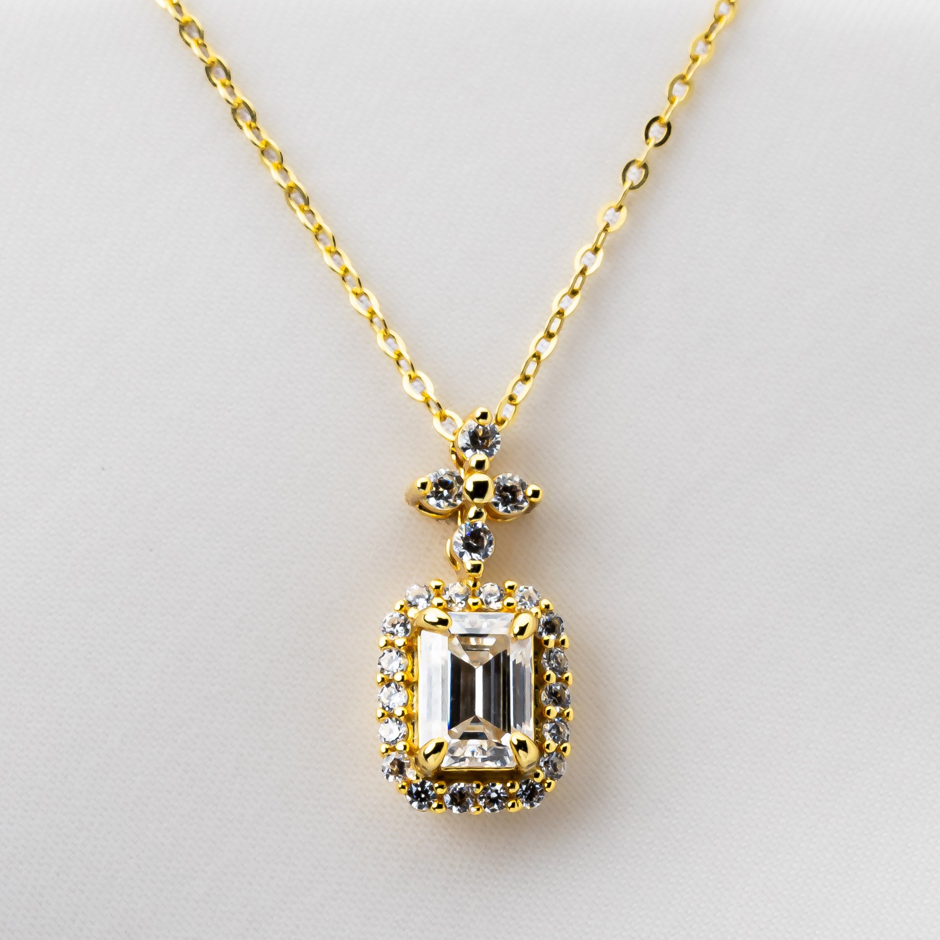 Gold necklace with a diamond-shaped pendant on a light gray background