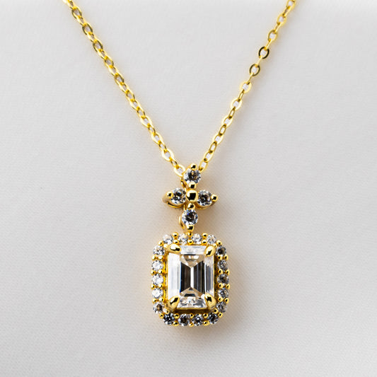 Gold necklace with a diamond-shaped pendant on a light gray background