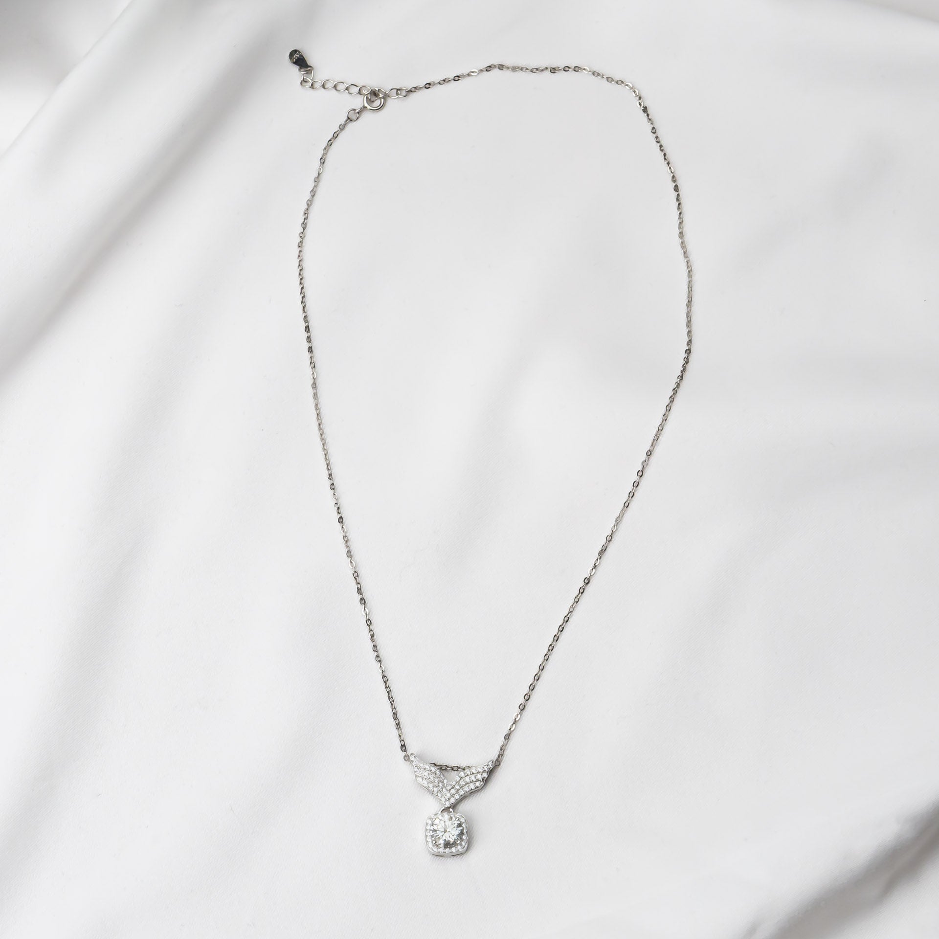 Silver necklace with a mossanite pendant on a light gray background